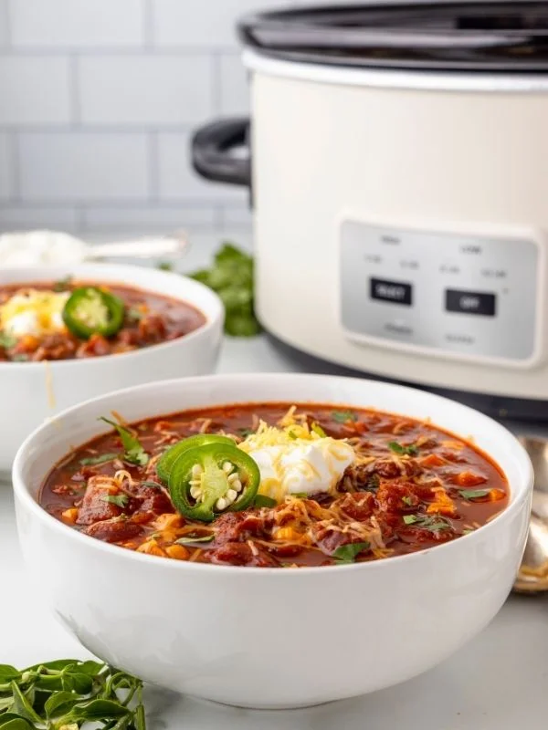 Tight shot on a bowl of chili with a slow cooker in the background