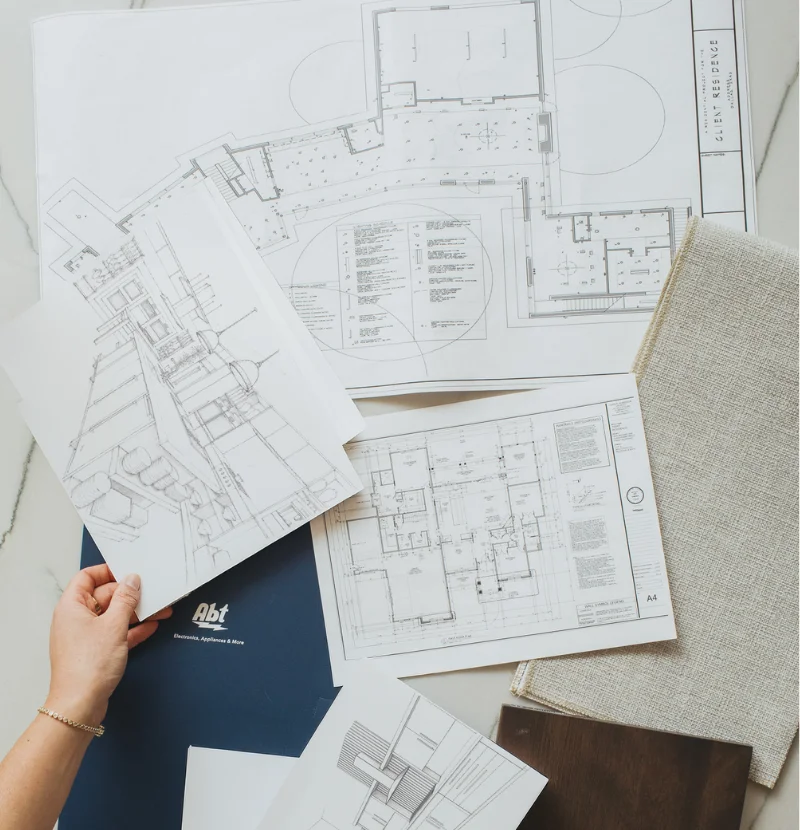 Overhead view of a person reviewing blueprints for a kitchen.