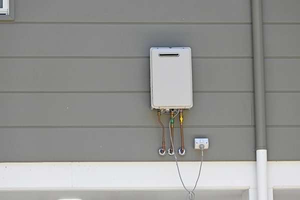 Tankless water heater on the exterior of a gray home
