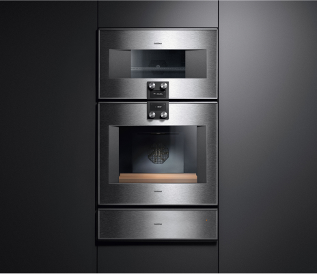 A sleek stainless steel oven accompanied by a Gaggenau warming drawer and built-in microwave