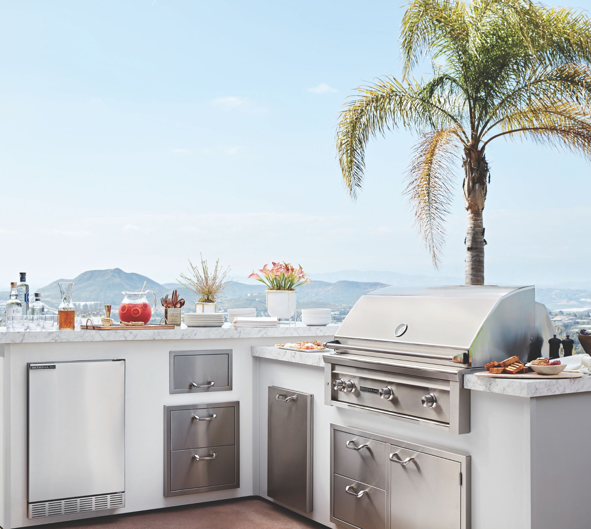 Wide shot of a luxury outoor kitchen showcasing a built in lynx grill with full outdoor kitchen accessories