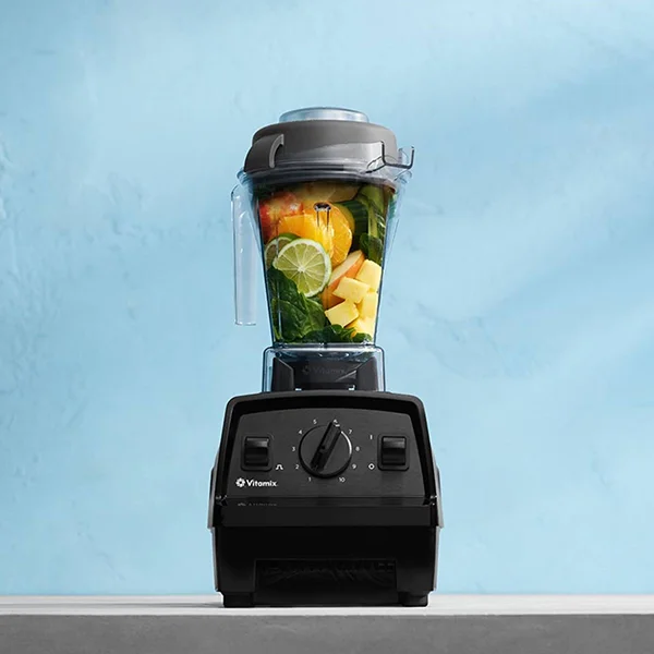 A black Vitamix blender filled with fruit sitting on a grey kitchen counter
