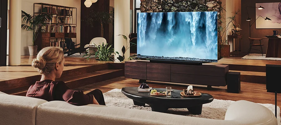 A woman sitting on a couch watching a waterfall scene on TV