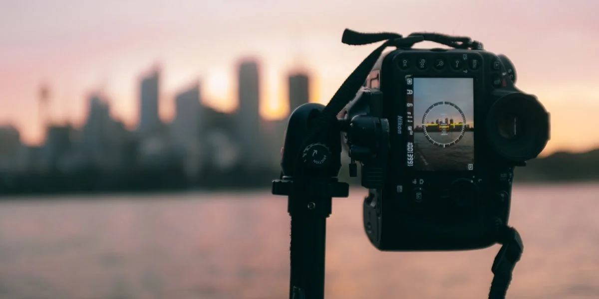A mirrorless camera set up on a tripod, capturing a photo of a city’s skyline.