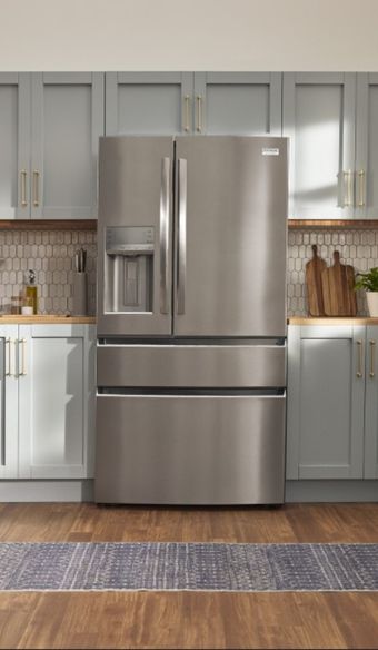 Tight close shot on a stainless steel french door frigidaire refrigerator built in to the kitchen cabnitry
