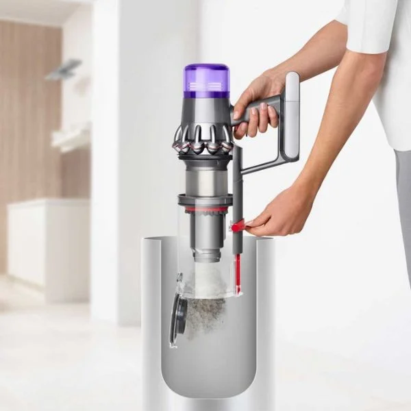 Side view of a person in a white shirt emptying the Dyson V11 over a trash bin.