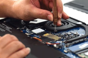 A person screwing in a screw on the inside of a laptop