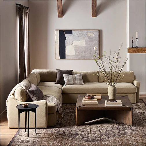 A cozy living room featuring a sectional couch, a coffee table, and a decorative rug on the floor.