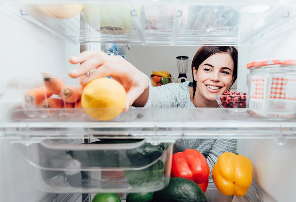 Person selecting fruit from inside a refrigerator