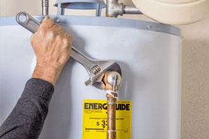 A man tightening a valve on a water heater