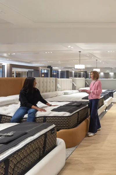 Two people sit at a table with design books, samples, and drawings of furniture