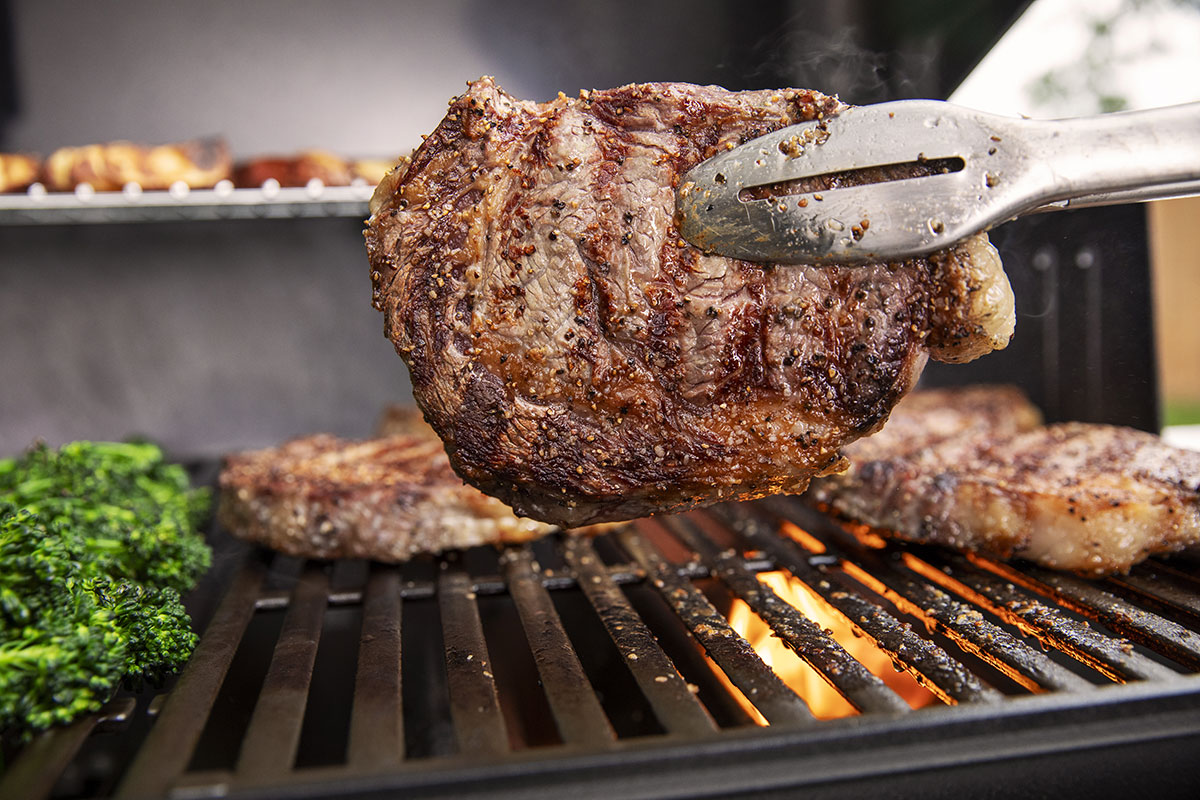 A cooked pork chop held by tongs.