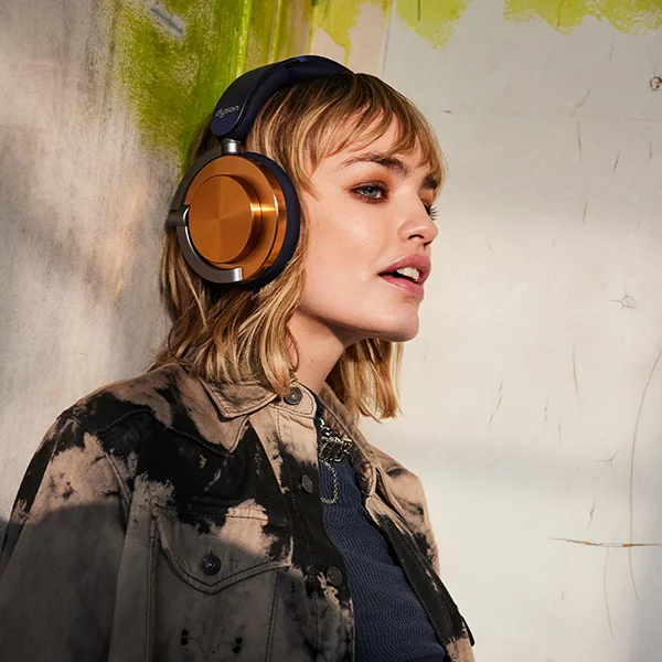 A woman wearing a pair of Dyson OnTrac headphones with copper ear caps