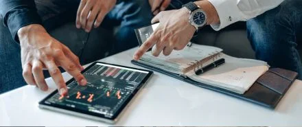 Two people sitting down using a tablet to get work done.