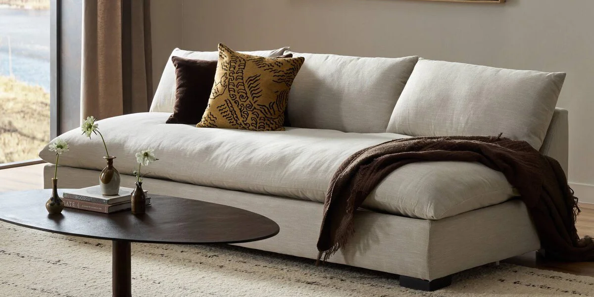 beige armless sofa with brown throw pillows