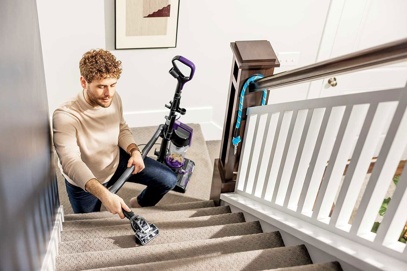 Lifestyle image of man vacuuming stairs