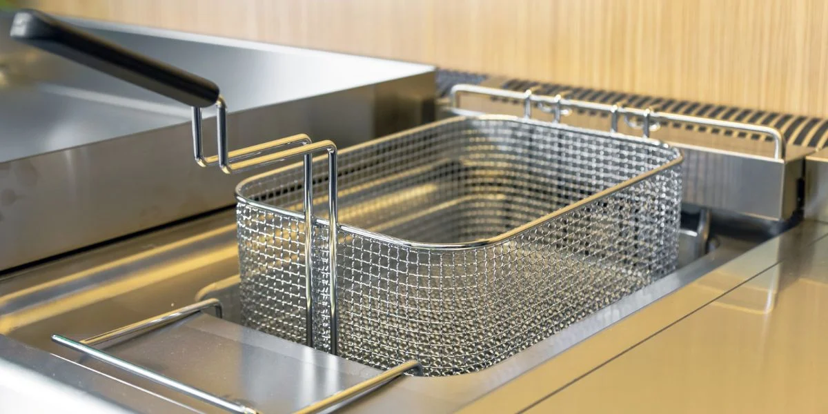 A clean deep fryer installed in a kitchen’s counters.