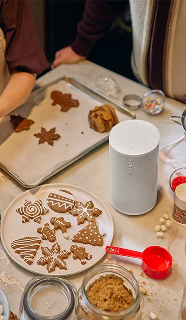 Sonos Era100 atop a kithen counter with holiday gingerbread cookies being baked