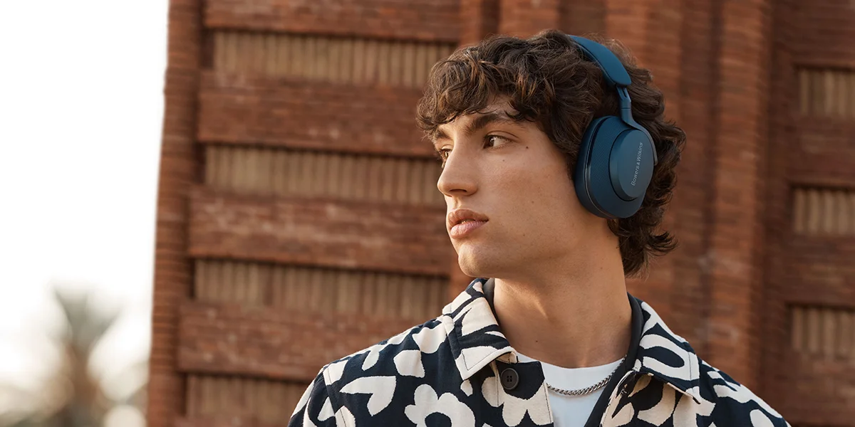 A man wearing a pair of ocean blue over-ear headphones outside
