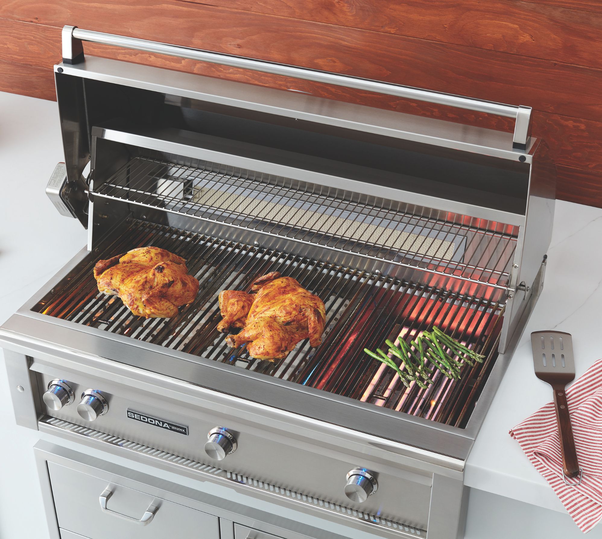 A sedona by lynx grill opened showcasing the large grilling surface cooking chicken and asparagus