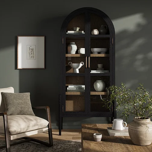 A living room scene with a chair, a table, a bookcase filled with books, and a cabinet for storage.