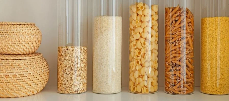 Kitchen storage in a pantry with several clear containers that show off different pastas, oats and more
