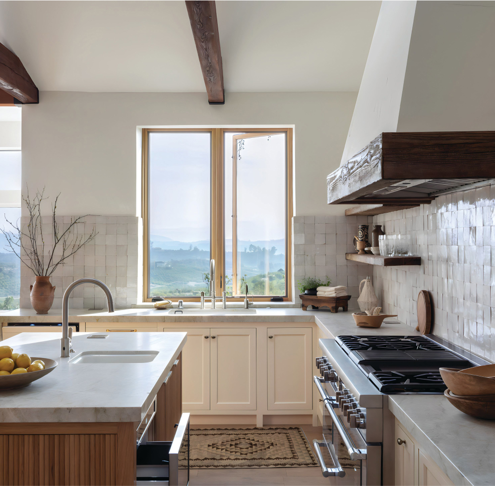 Modern kitchen featuring Thermador appliances, with picturesque mountain scenery visible through the large glass windows