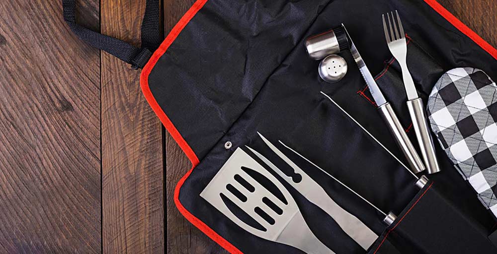 Grill Apron on wood background with grilling accessories and tools in pockets