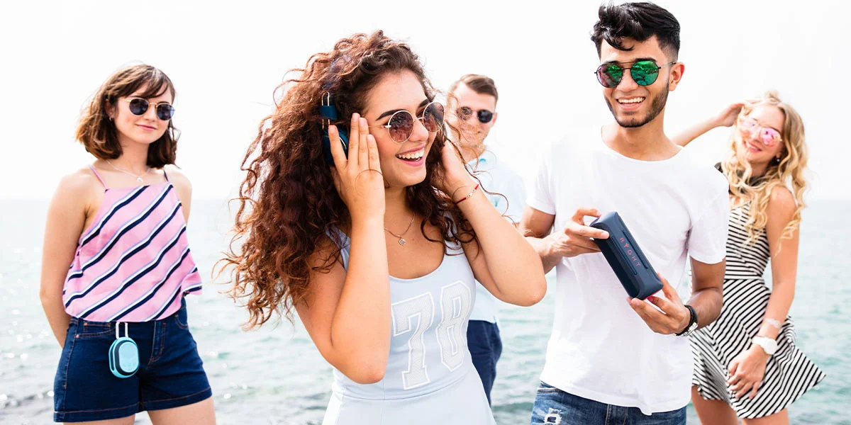 A group of friends listening to music on a portable speaker.