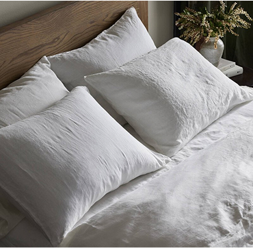 A white bed adorned with soft white pillows and a stylish wooden headboard, enhancing the room's elegance