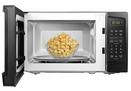 Front of open microwave with bwol of popcorn inside.