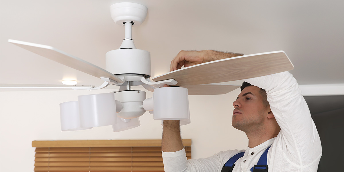 Man standing on step stool changing the direction of a ceiling fan.