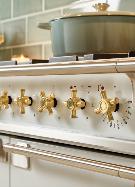 Close-up of a gas stove's brass knobs on an AGA range, emphasizing the stylish design and quality materials used