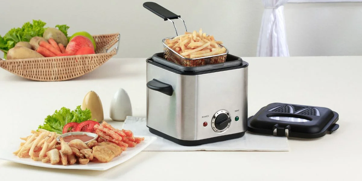 A compact, countertop deep fryer with French fries in the basket.