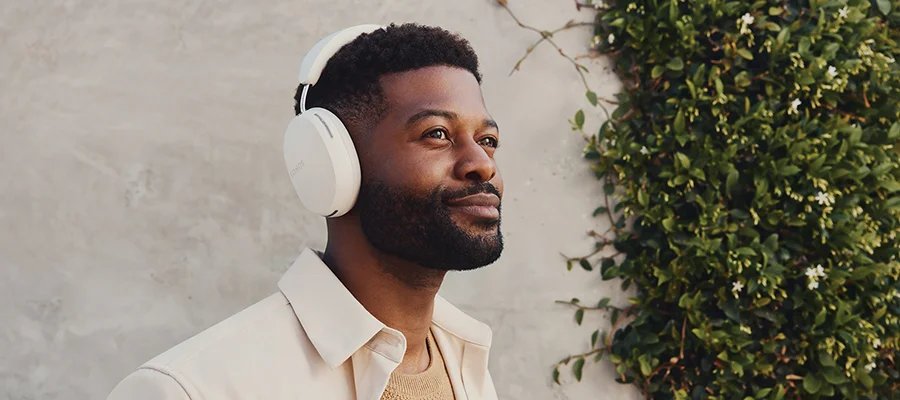 A man standing outside wearing a white pair of Sonos Ace headphones