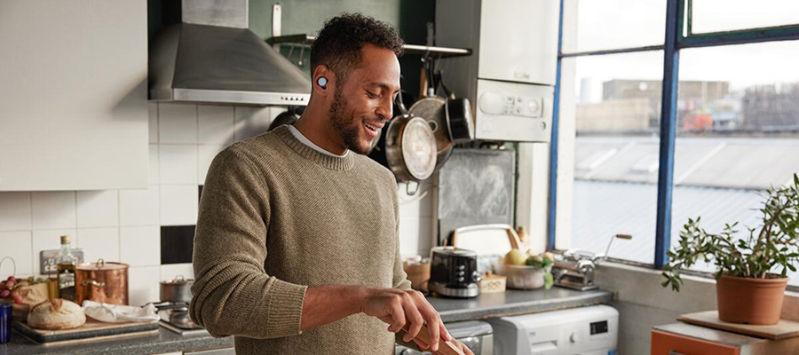A man wearing Google Pixel Buds while cooking in his kitchen