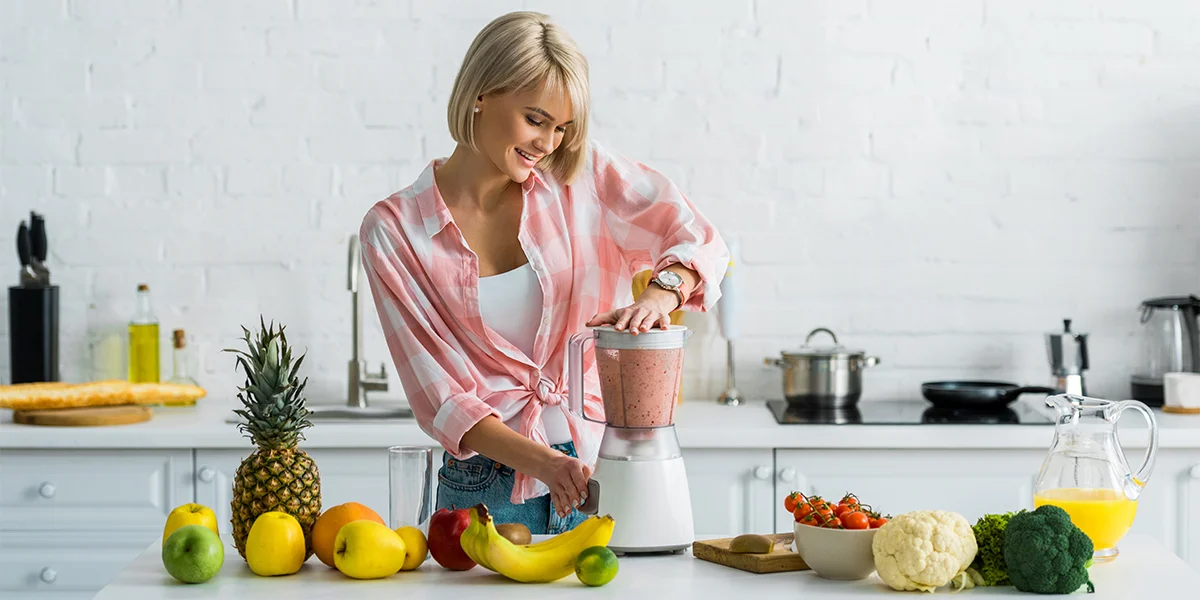 Woman making a smoothie in the blender in her kitchen.