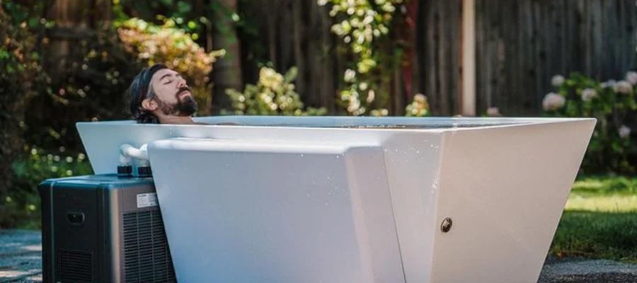 A man relaxing in a cold plunge in his outdoor yard space