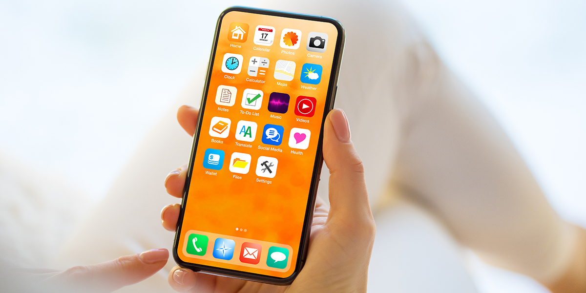Someone holding a smartphone with a variety of different apps on the home screen