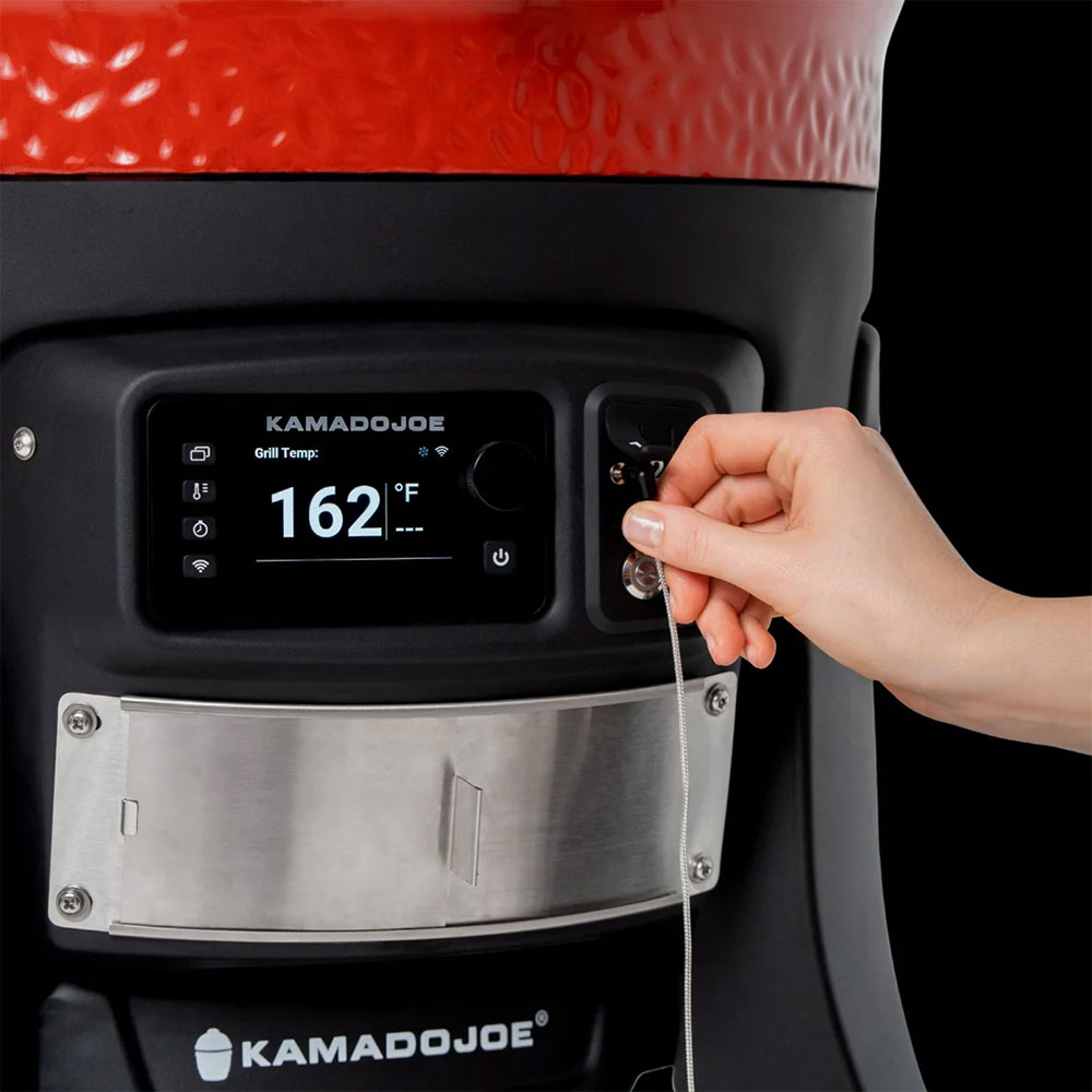 Person Plugging in Temperture Probe Cord Into a Kamado Joe Charcoal Smoker and Grill