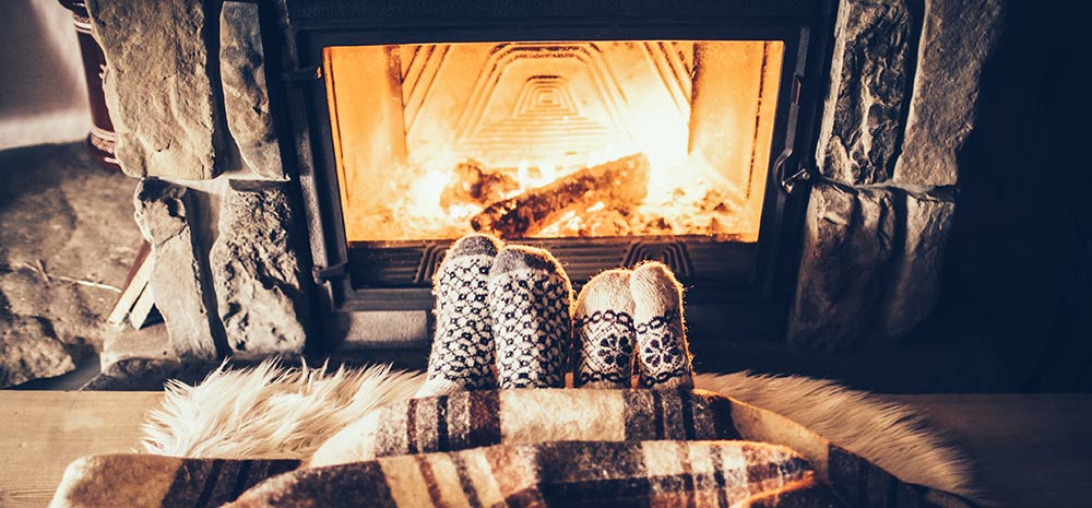 People under a blanket with fireplace in front of them
