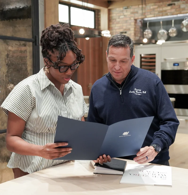 An Abt employee reviews a contract in a blue folder with a female customer.