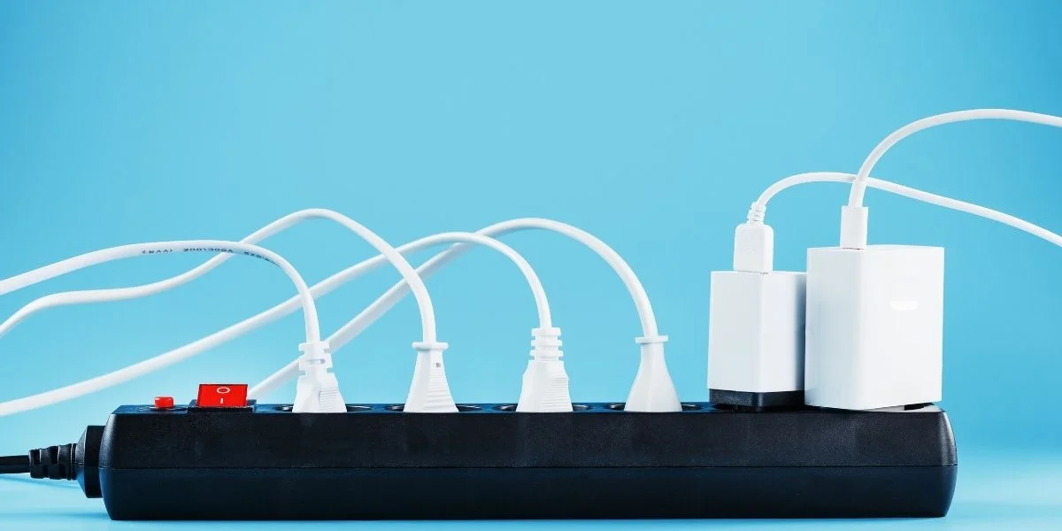 A black power strip filled with white cords and two chargers