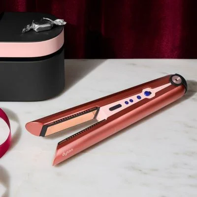 Dyson Corrale hair straightener in pink beside its accessories and case