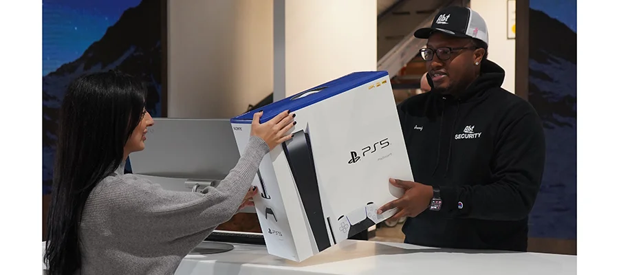 An Abt customer service employee giving a customer a PS5 at the merchandise pickup desk