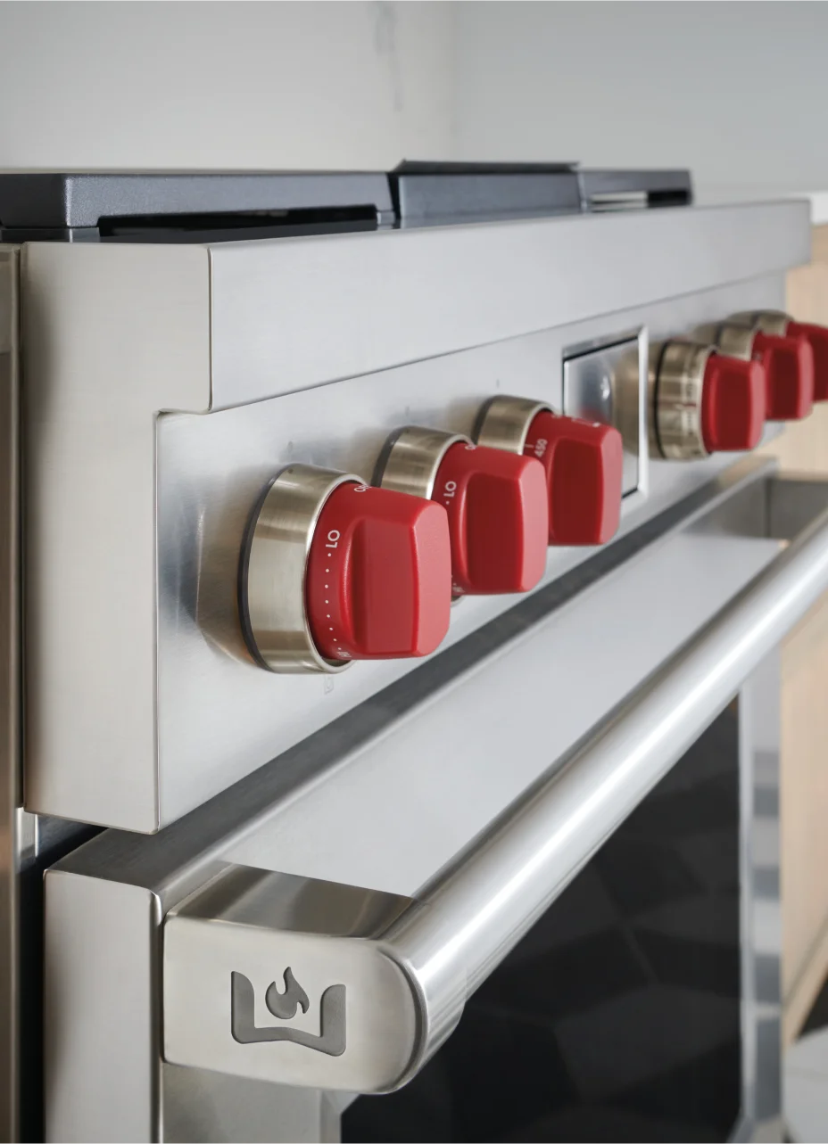 Close-up of the iconic red Wolf range knobs, featuring the Wolf logo and detailed design