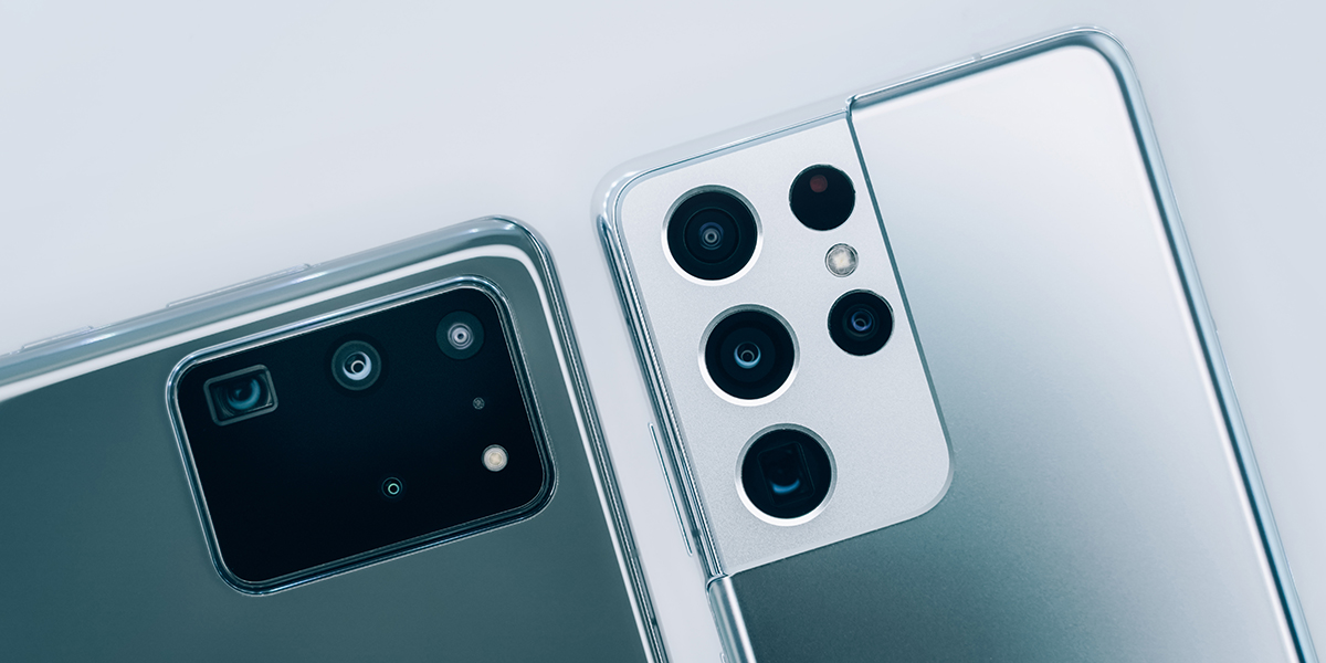 Two cell phones face down showing their multiple camera lenses