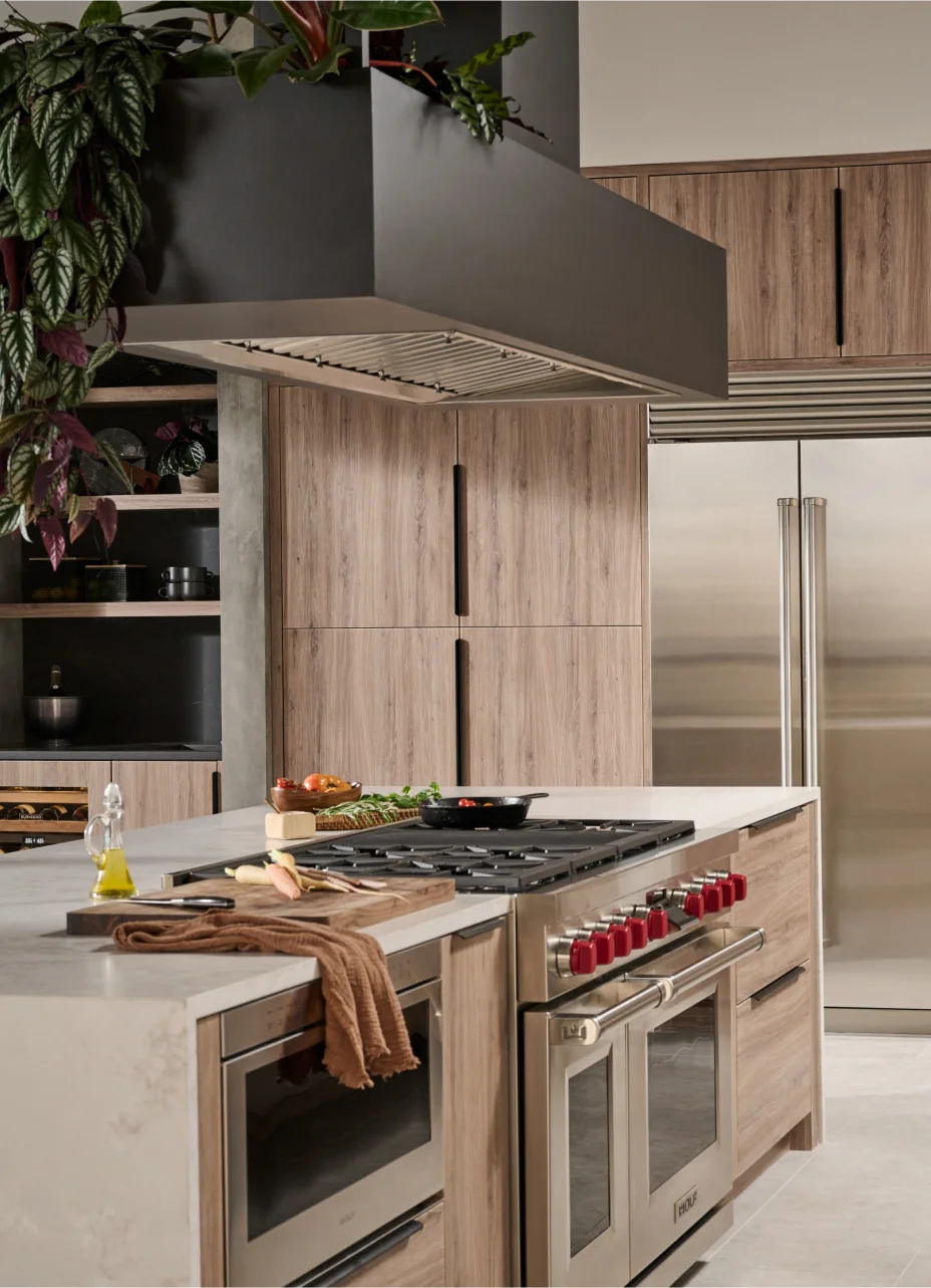 Modern kitchen with wooden cabinets and high-end Wolf appliances, including a ventilation hood, refrigerator, built-in microwave and range