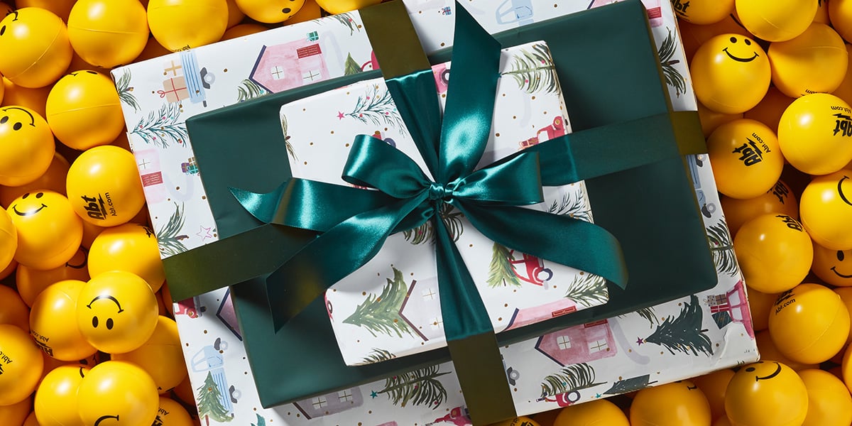 Pile of presents wrapped in a bow sitting atop smiley face balls
