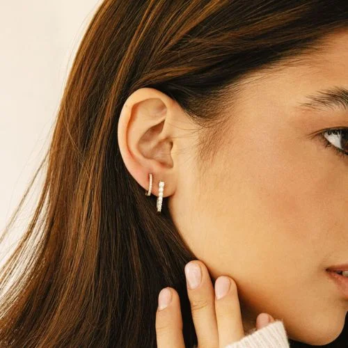 Warm colored tight shot on persons ear with two small Dana Rebecca earrings in